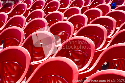 Image of Bright plastic chairs standing in a row.