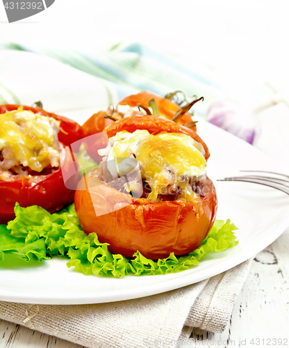 Image of Tomatoes stuffed with rice and meat with lettuce in plate on boa