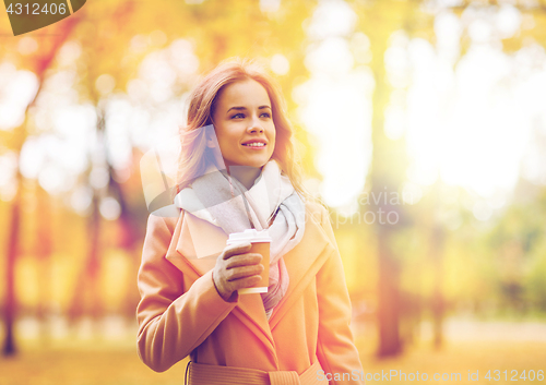 Image of happy young woman drinking coffee in autumn park