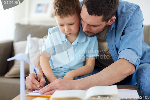 Image of father and son with toy wind turbine at home