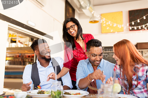 Image of happy friends eating at restaurant