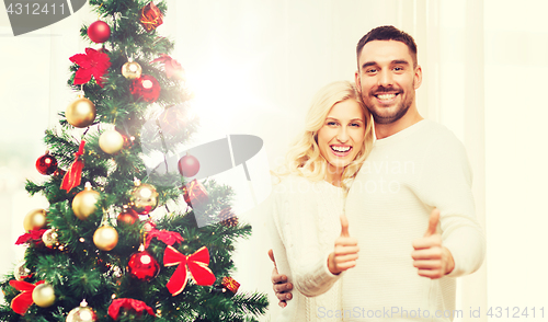 Image of happy couple showing thumbs up with christmas tree