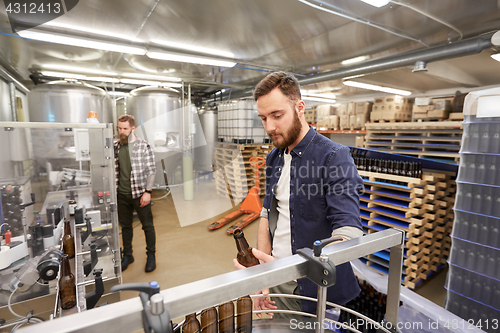 Image of men with bottles on conveyor at craft beer brewery