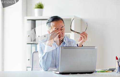 Image of tired businessman with glasses at laptop in office
