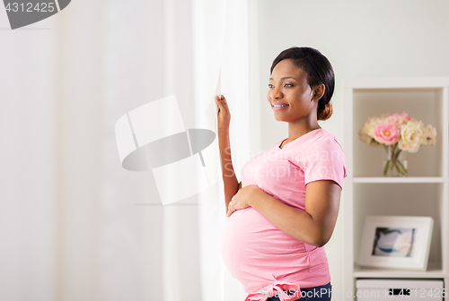 Image of happy pregnant woman with big belly at home