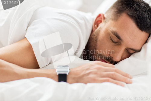 Image of close up of man with smartwatch sleeping in bed