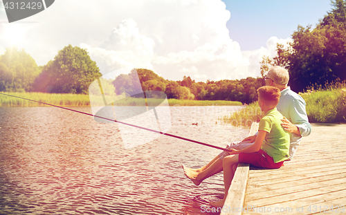 Image of grandfather and grandson fishing on river berth