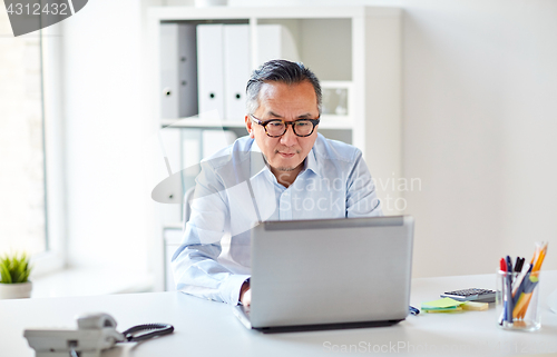 Image of businessman in eyeglasses with laptop office