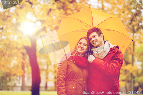 Image of smiling couple with umbrella in autumn park