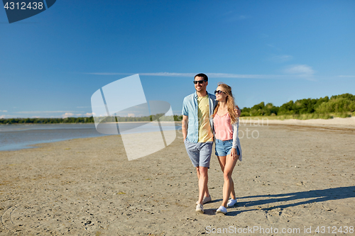 Image of happy couple walking along summer beach