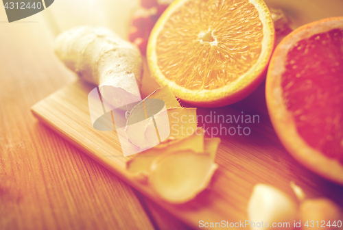 Image of citrus fruits, ginger and garlic on wood