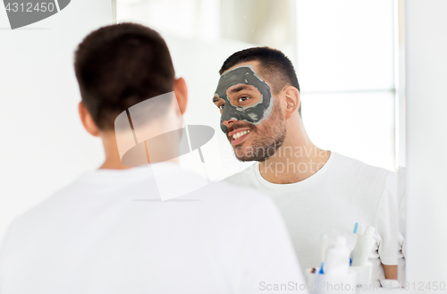 Image of young man with clay mask on face at bathroom