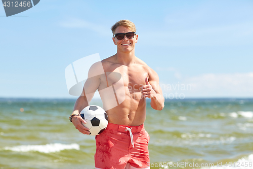 Image of young man with soccer ball on beach