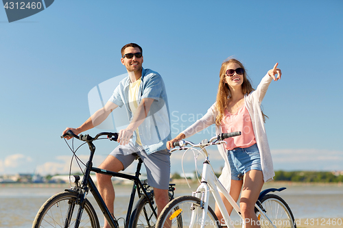 Image of happy young couple riding bicycles at seaside