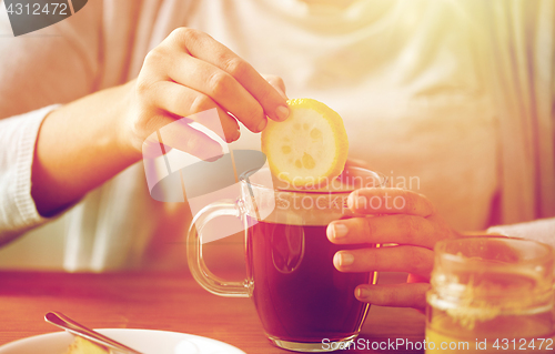 Image of close up of woman adding lemon to tea with honey