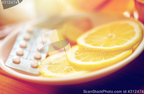 Image of lemon slices, pills and ginger on plate