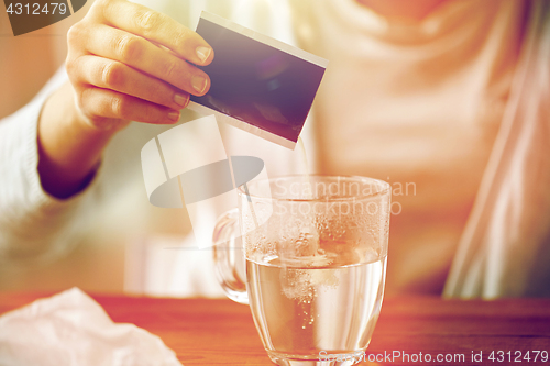 Image of woman pouring medication into cup of water