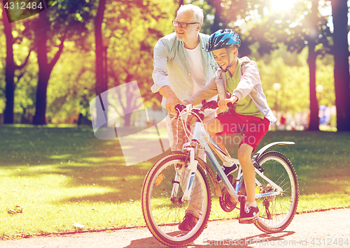 Image of grandfather and boy with bicycle at summer park