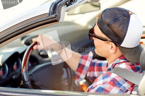 Image of happy young man in shades driving convertible car