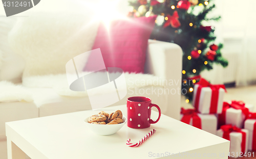 Image of close up of christmas cookies, sugar cane and cup