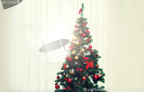 Image of christmas tree in living room over window curtain