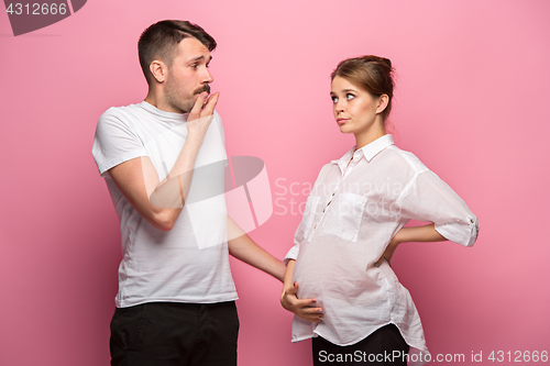 Image of The funny surprised handsome man and his beautiful pregnant wife\'s tummy