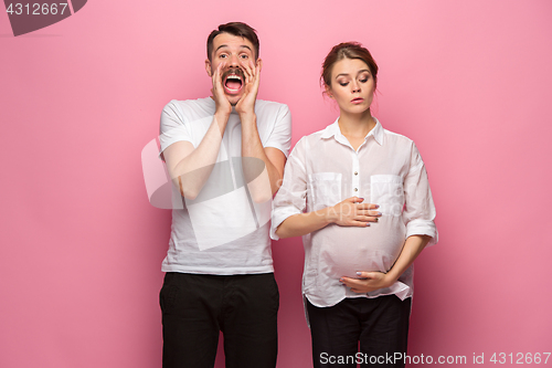 Image of The funny surprised handsome man and his beautiful pregnant wife\'s tummy