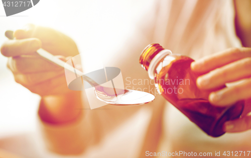 Image of woman pouring medication from bottle to spoon