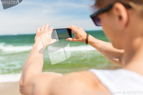 Image of man with smartphone photographing on summer beach