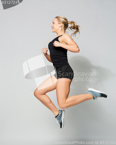 Image of young woman in black sportswear jumping