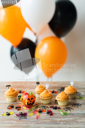 Image of halloween party decorated cupcakes on wooden table