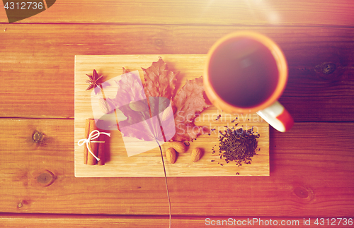 Image of cup of tea, maple leaf and almond on wooden board