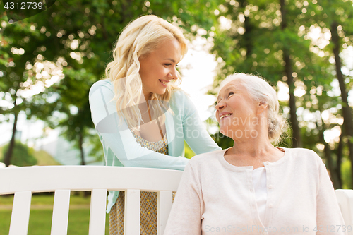 Image of daughter with senior mother hugging on park bench