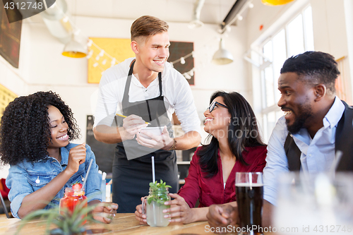 Image of waiter and friends with menu and drinks at bar