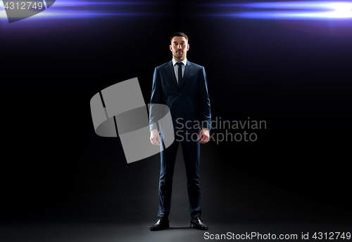 Image of businessman in suit over black with laser light