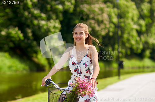 Image of happy woman riding fixie bicycle in summer park