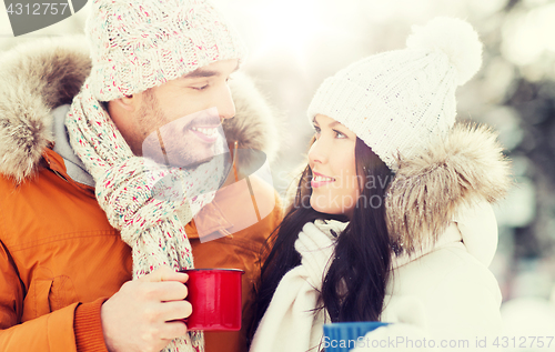 Image of happy couple with tea cups over winter landscape