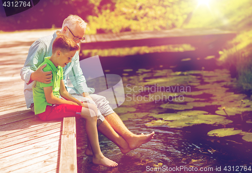 Image of grandfather and grandson sitting on river berth