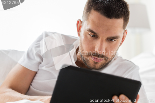 Image of close up of man with tablet pc in bed at home