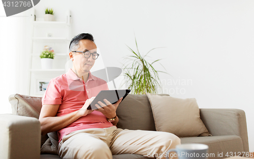 Image of man with tablet pc sitting on sofa at home