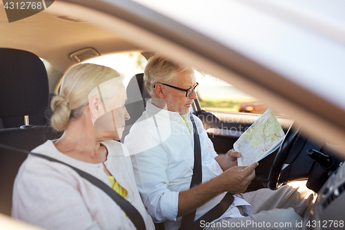 Image of happy senior couple with map driving in car