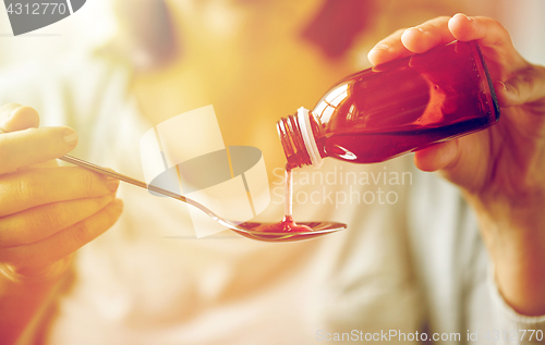 Image of woman pouring medication from bottle to spoon