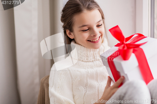 Image of happy beautiful girl with christmas gift at home