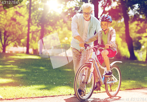 Image of grandfather and boy with bicycle at summer park