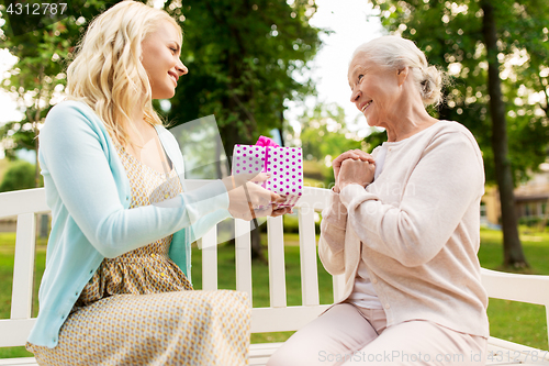 Image of daughter giving present to senior mother at park