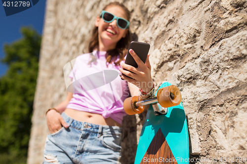 Image of happy teenage girl with longboard and smartphone