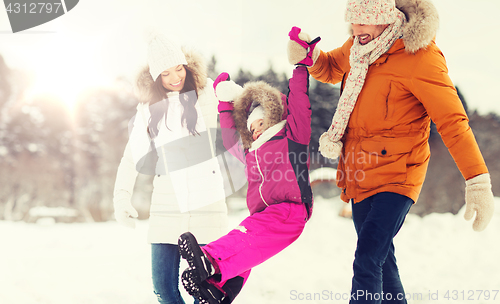 Image of happy family in winter clothes walking outdoors