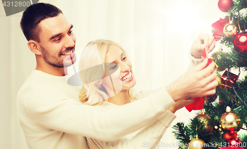 Image of happy couple decorating christmas tree at home