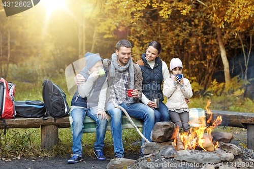 Image of happy family sitting on bench at camp fire