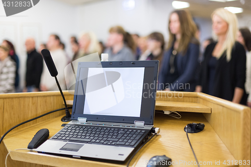 Image of Laptop computer and microphotone at podium on business conference event.